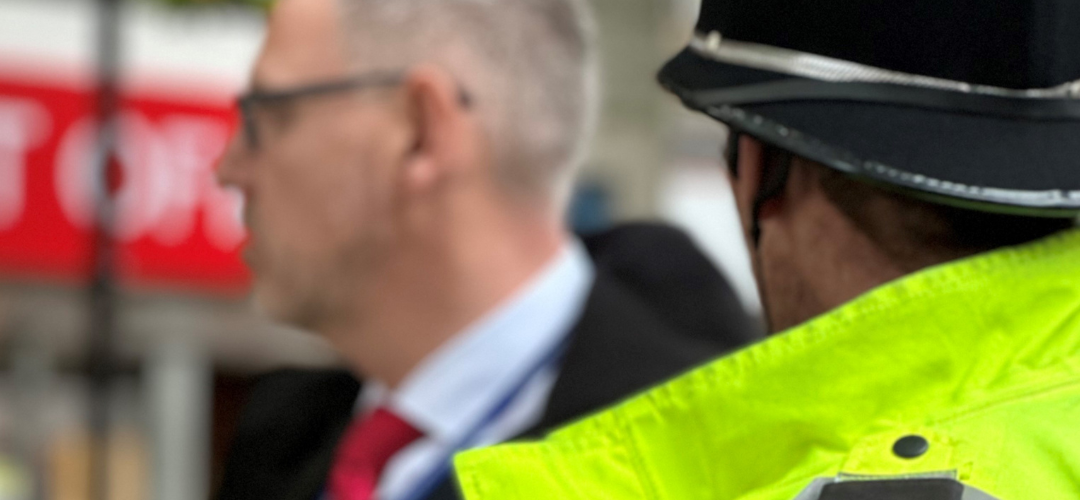 Man in police uniform alongside man in suit outside shop