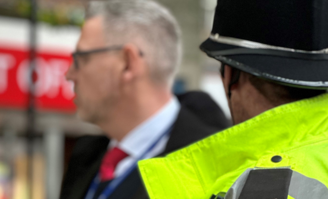 Man in police uniform alongside man in suit outside shop